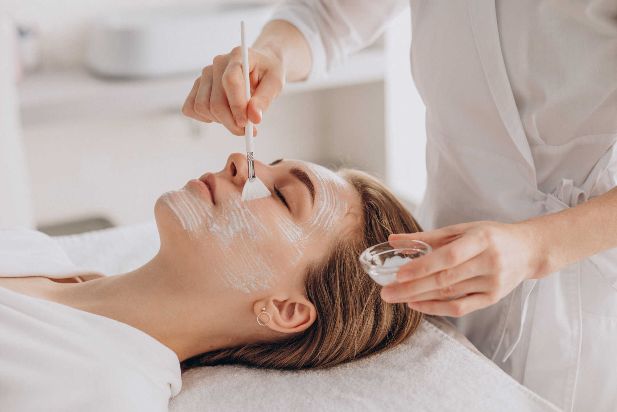 cosmetologist doing face treatment applying face mask scaled 1
