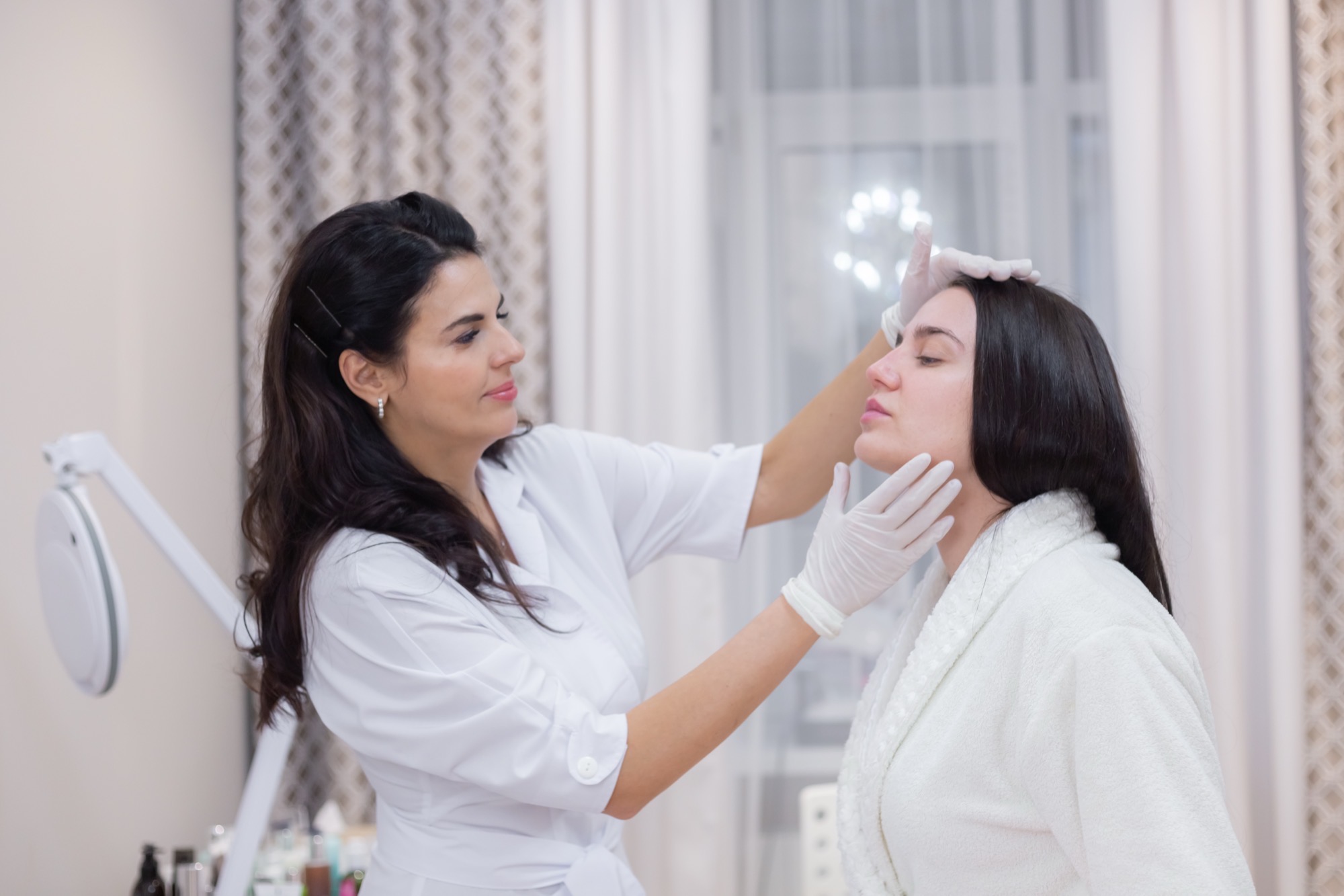 Full Face Harmonisation 1 Aesthetic practitioner assessing a woman's facial proportions at a consultation